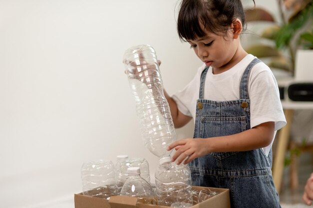 Klein meisje met plastic flessen voor recycling