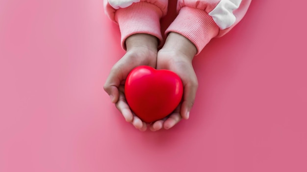 Klein meisje met rood hart in de hand op roze achtergrond