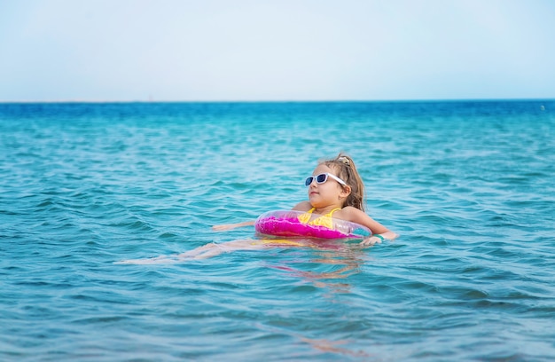 Klein meisje met roze opblaasboot in de zee