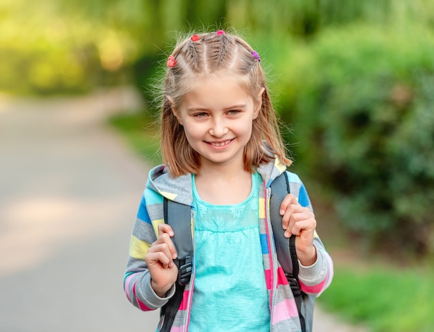 Klein meisje met rugzak die door parksteeg naar school gaat