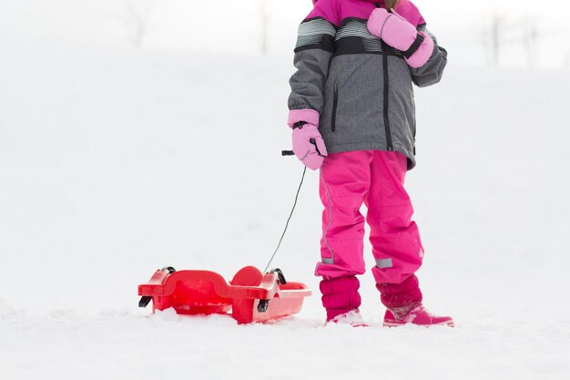 Foto klein meisje met slee buiten in de winter