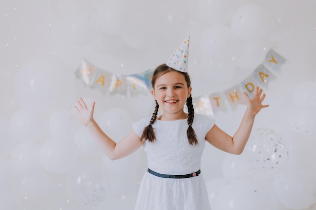 klein meisje met twee staartjes in een witte jurk viert haar verjaardag