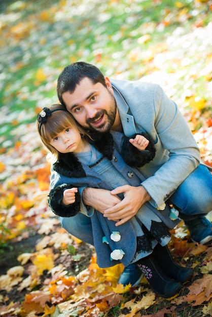Klein meisje met vader spelen in herfst park.