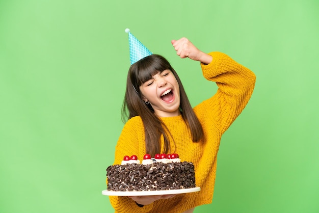 Klein meisje met verjaardagstaart over geïsoleerde chroma key achtergrond die een overwinning viert