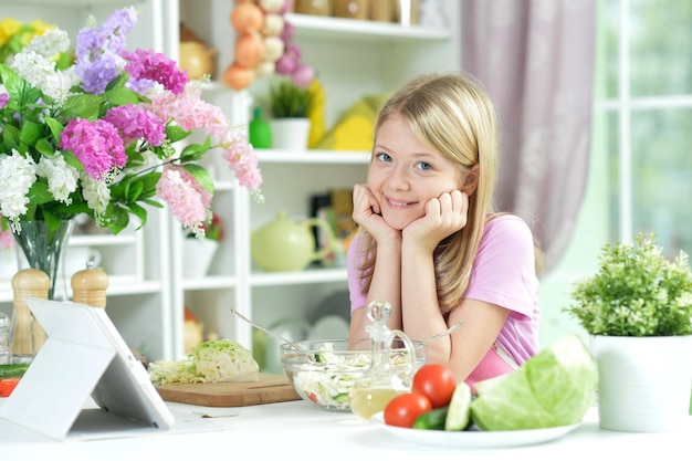 Klein meisje met verse salade in glazen kom