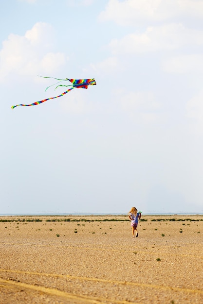 Klein meisje met vlieger in het zomerwoestijnlandschap