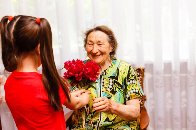 Klein meisje op bezoek bij haar zieke grootmoeder die bloemen geeft