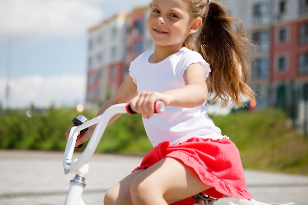 Klein meisje op een fiets in het zomerpark buiten fietsen