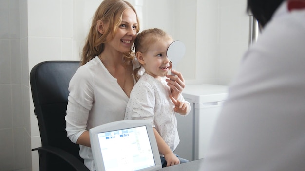 Klein meisje - patiënt in oogartskamer - kind met mama op consultatie, close-up