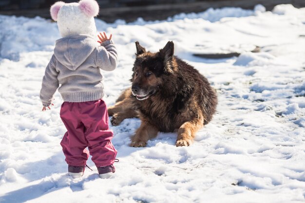 Klein meisje praat met haar hond op winterwandeling
