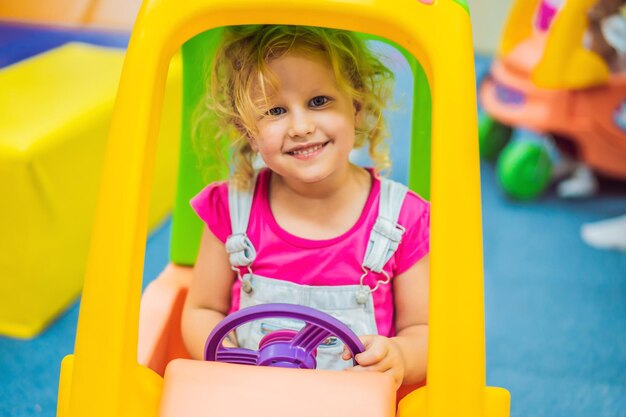 Klein meisje rijdt in een kleurrijke speelgoedauto