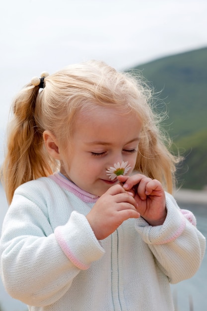 Klein meisje ruikt kamille aan de kust