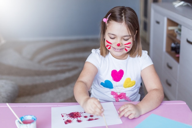 Klein meisje schilderen met haar handen en vingers thuis
