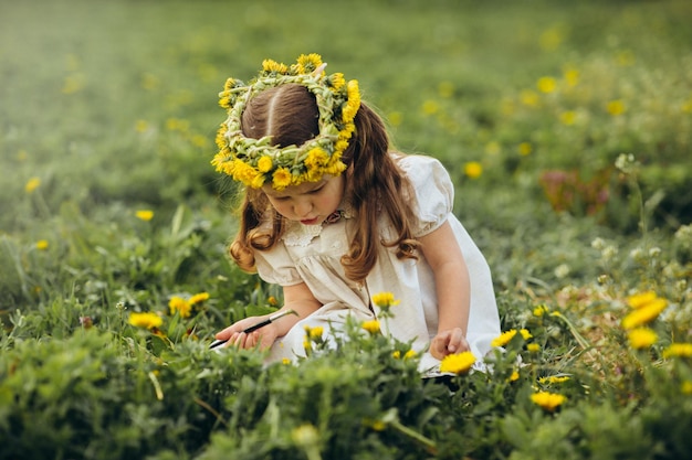 klein meisje schildert met een penseel bloemen in het veld