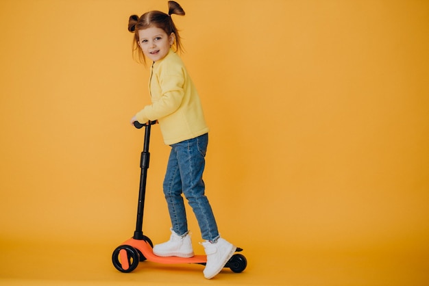 Klein meisje scooter rijden in studio