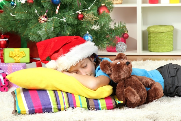 Klein meisje slaapt bij de kerstboom