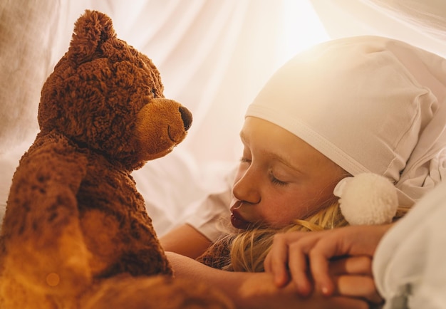 Klein meisje slaapt met haar teddybeer op haar bed in een tent met slaapkop thuis zoete dromen concept afbeelding