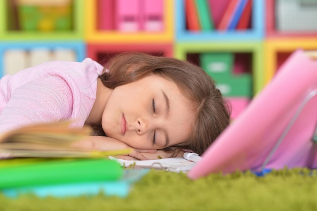 Klein meisje slaapt op stapel boeken