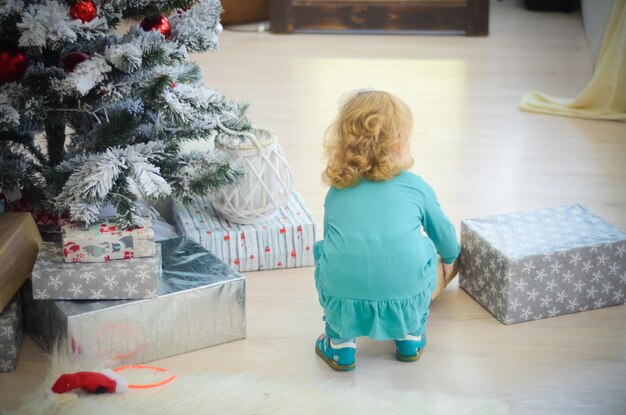 Klein meisje speelt in de kamer met kerstversieringen en ingepakte cadeautjes