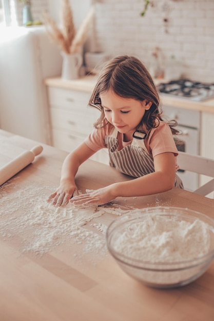 Klein meisje speelt met bloem in de keuken