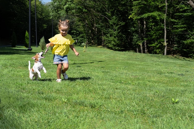 Klein meisje speelt met haar hond Jack Russell Terrier in het park