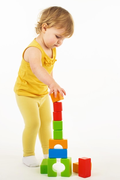 klein meisje speelt met kleurrijke speelgoedblokken