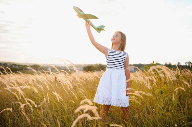 Klein meisje speelt met speelgoedvliegtuig in het veld