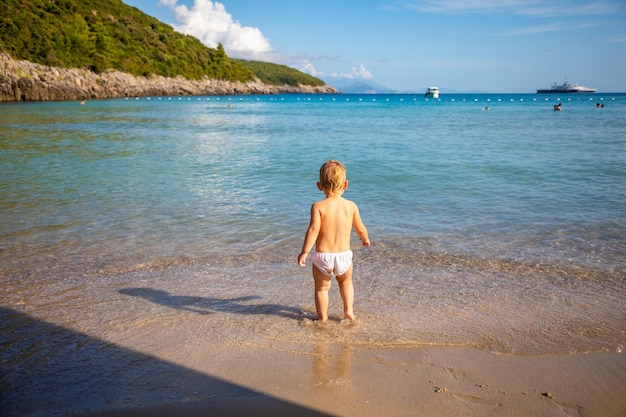 Klein meisje speelt met zand op het strand en geniet van een heerlijke vakantie