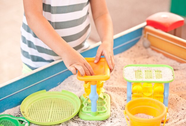 Klein meisje speelt op de buitenspeeltuin met zand en speelgoed