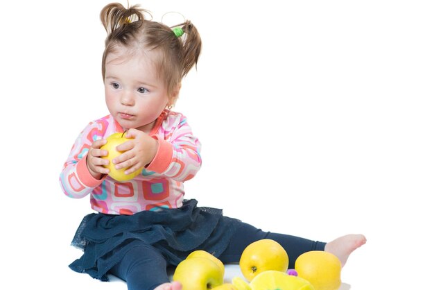 Klein meisje spelen met appels op een witte achtergrond