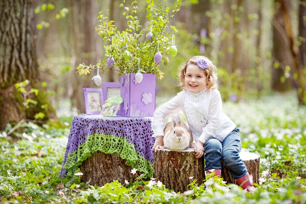 Klein meisje spelen met echt konijn in de tuin. Lachend kind bij paaseierenjacht met huisdierenkonijntje. Lente buitenplezier voor kinderen met huisdieren