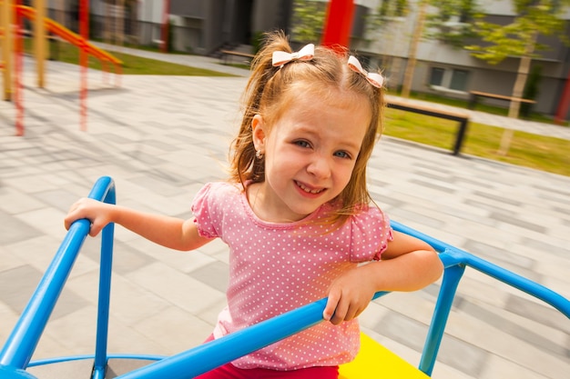 Klein meisje spelen op de carrousel op de buitenspeeltuin.