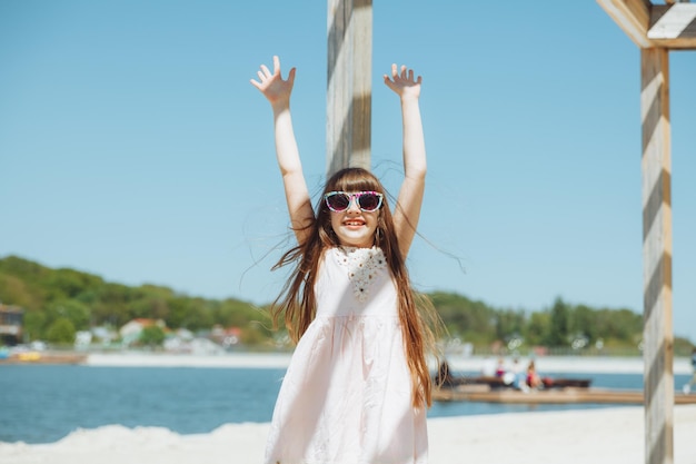 Klein meisje springt op het strand aan de oever van het stadsstrand in de zomervakantie