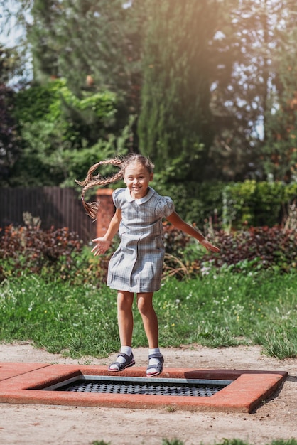 Klein meisje springt op trampoline in een park Gelukkig lachend kind buiten in de tuin op zomervakantie Spring hoog