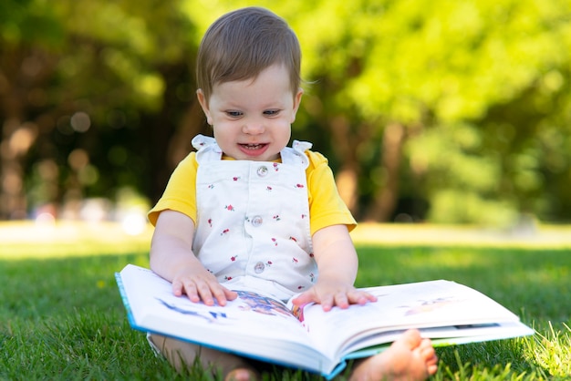 Klein meisje studeert een boek vroege peuter ontwikkeling verrukking baby buiten in het park