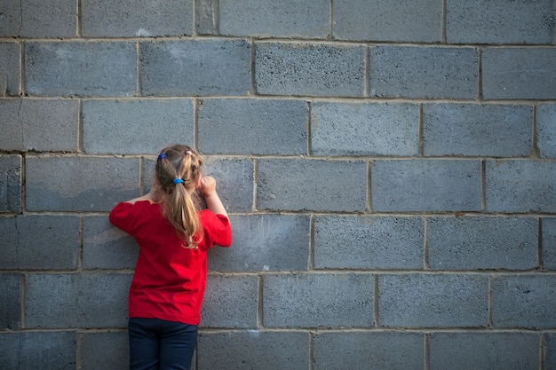 Klein meisje tekent op een grijze bakstenen muur