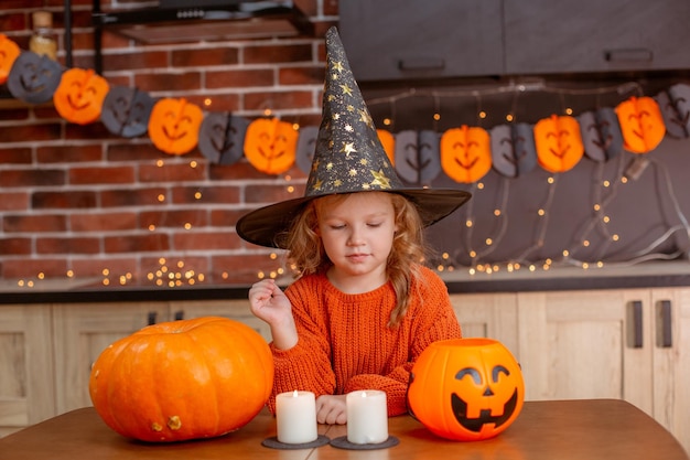 Klein meisje thuis in de keuken aan tafel met een pompoen voor halloween