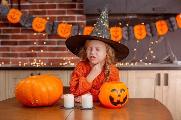 Klein meisje thuis in de keuken aan tafel met een pompoen voor halloween