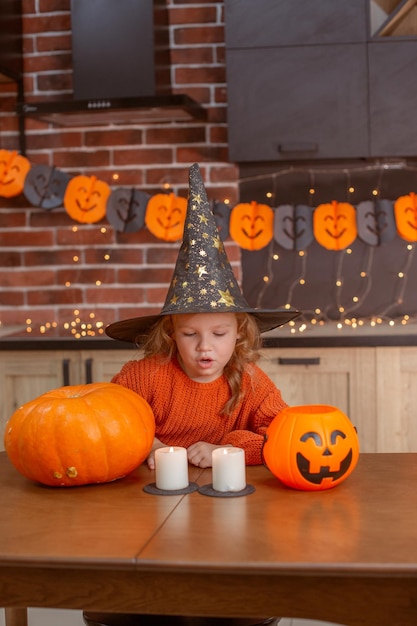 Klein meisje thuis in de keuken aan tafel met een pompoen voor halloween