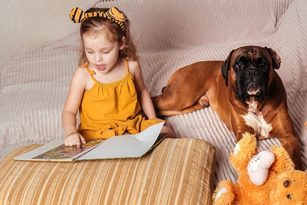 Klein meisje thuis op de bank een boek lezend aan haar grote hond