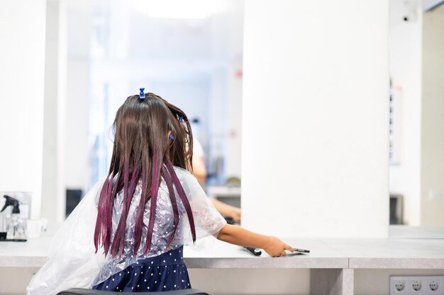 klein meisje verft haar haar paars in een kapsalon