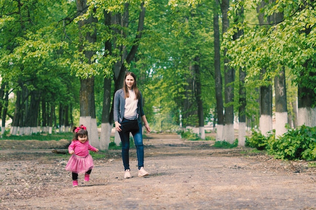 klein meisje vergezeld door haar moeder op een mooie zomerdag wandelen door een klein bos insid