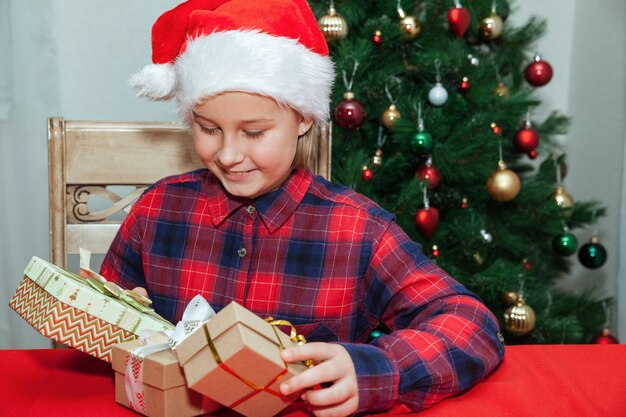 Klein meisje verheugt zich in geschenken op de achtergrond van de kerstboom