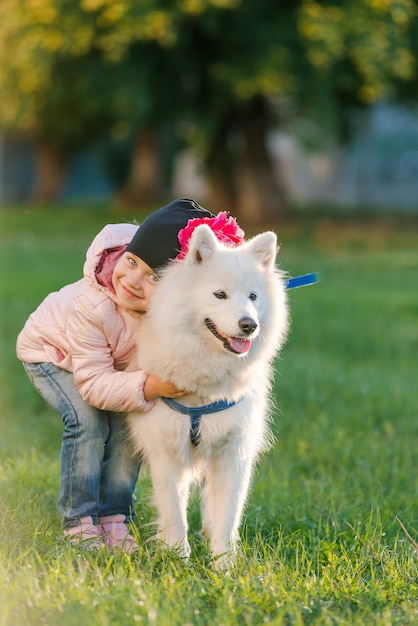 Klein meisje wandelt met haar hond Samojeed in het park in de herfst
