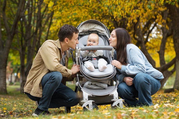 Klein meisje zit in kinderwagen tussen jonge mama en papa