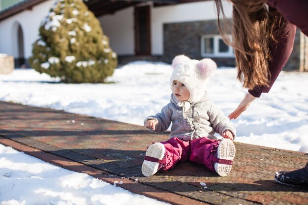 Klein meisje zit onderweg in waterdichte broek op koude zonnige winterdag