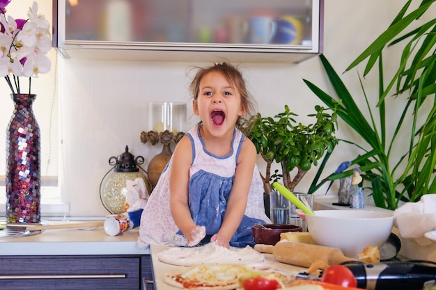 Klein meisje zit op een tafel in een keuken en probeert dieetpap te maken.