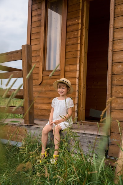 Klein meisje, zittend op de trap van een houten huis