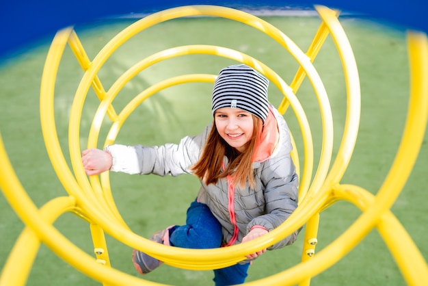 Klein meisje zittend op gele spiraal kinderen glijden op speelplaats in de herfsttijd