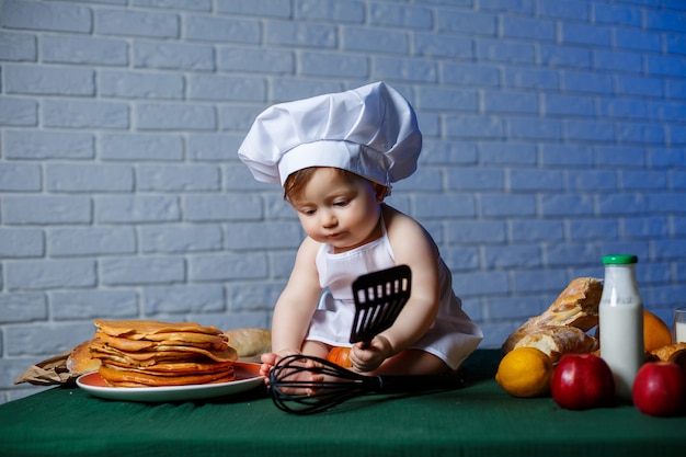 Klein mooi kind gekleed in een schort, kookkostuum voor kinderen